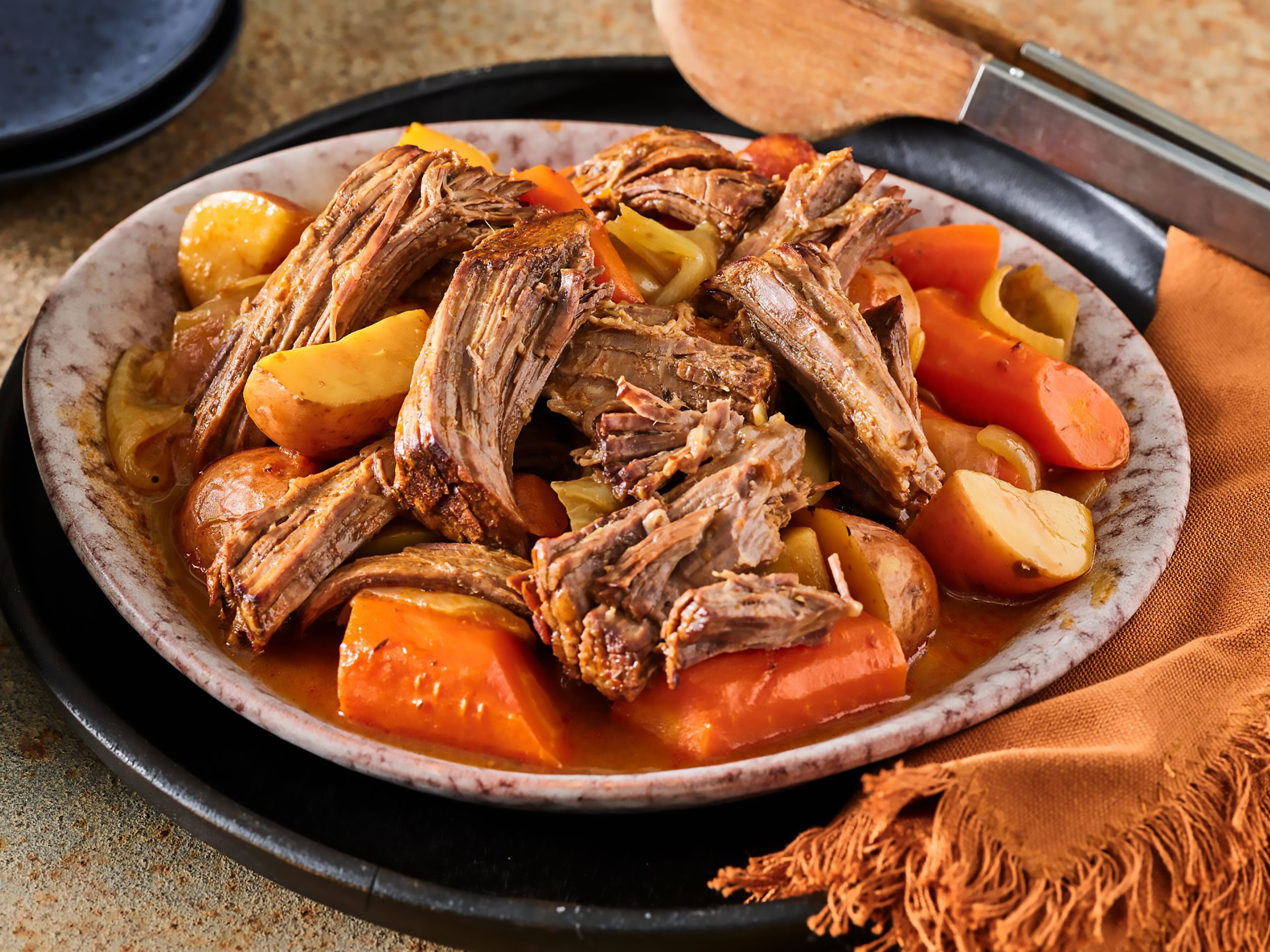 Savory slow-cooked beef roast served with a medley of carrots, potatoes, and onions, showcasing a rich, flavorful broth in a rustic dish. Perfect for hearty family meals or comfort food gatherings.
